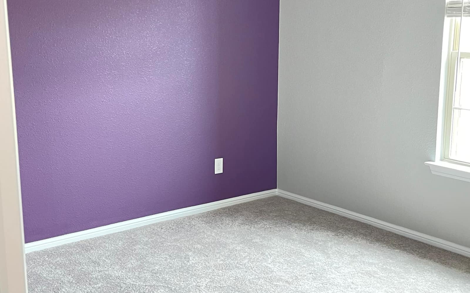 A finished bedroom painted by JC Painting Services, with a deep purple accent wall meeting soft grey walls and white baseboards